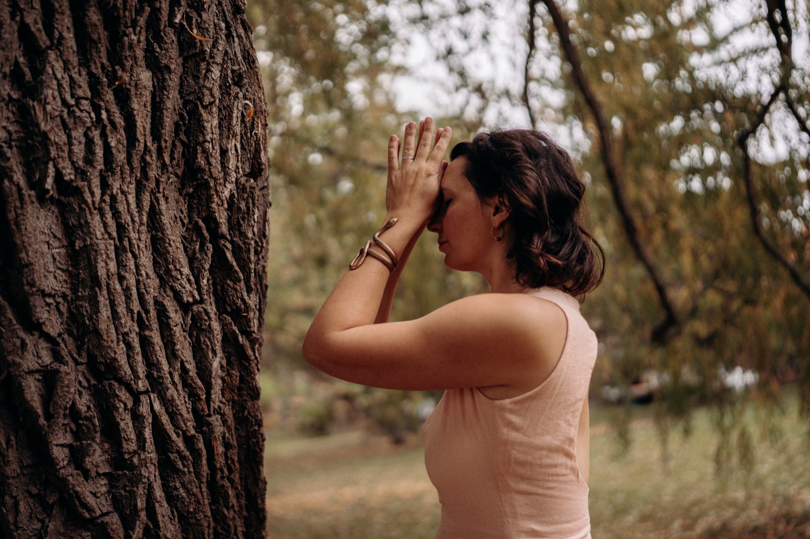 A practitioner resting in stillness against a tree